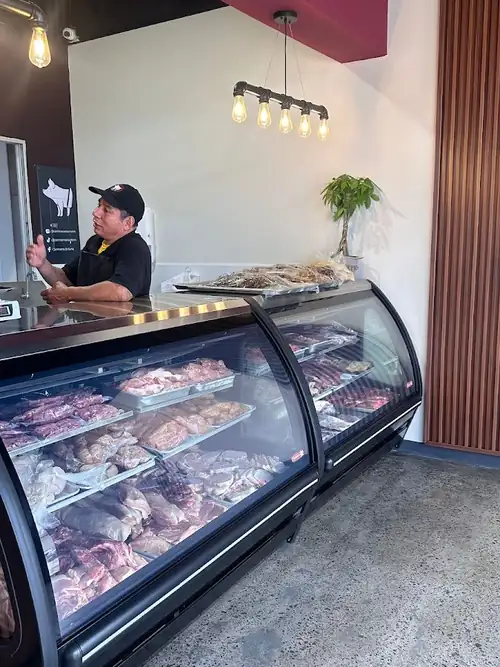 Interior de Carnicería El Corte: la vitrina con los cortes del día y el equipo atendiendo