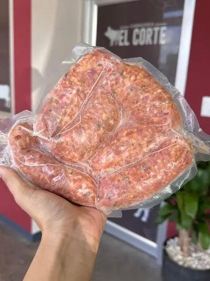 Bolsa de El Corte en mano, con el rótulo de la tienda al fondo